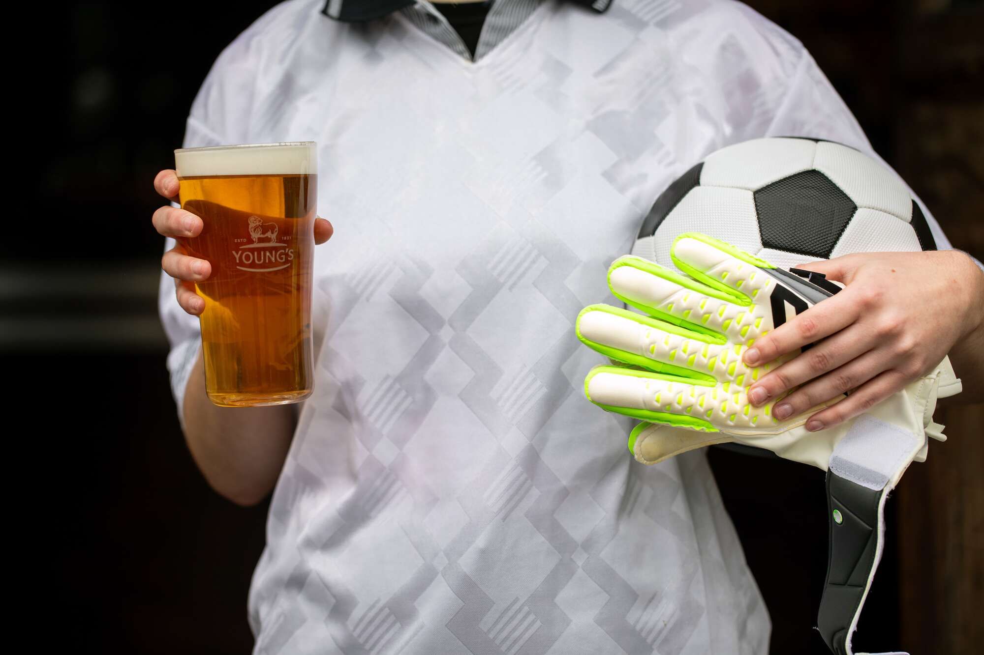 Woman with beer in one hand and football and gloves in the other